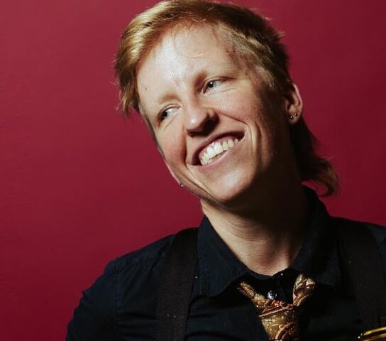 Red background with non binary person smiling