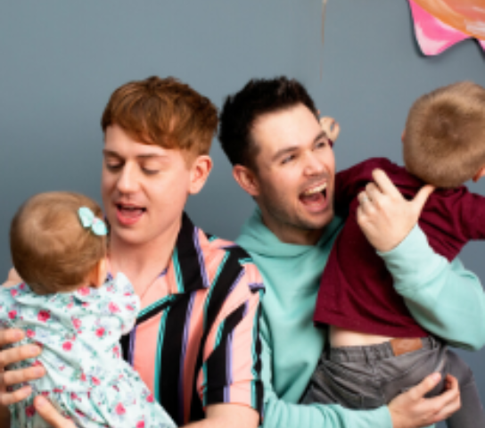 Two dads holding their children.