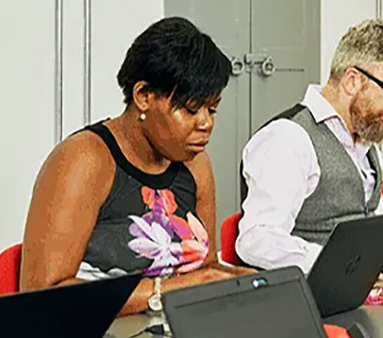 Employees in a meeting room working on laptops