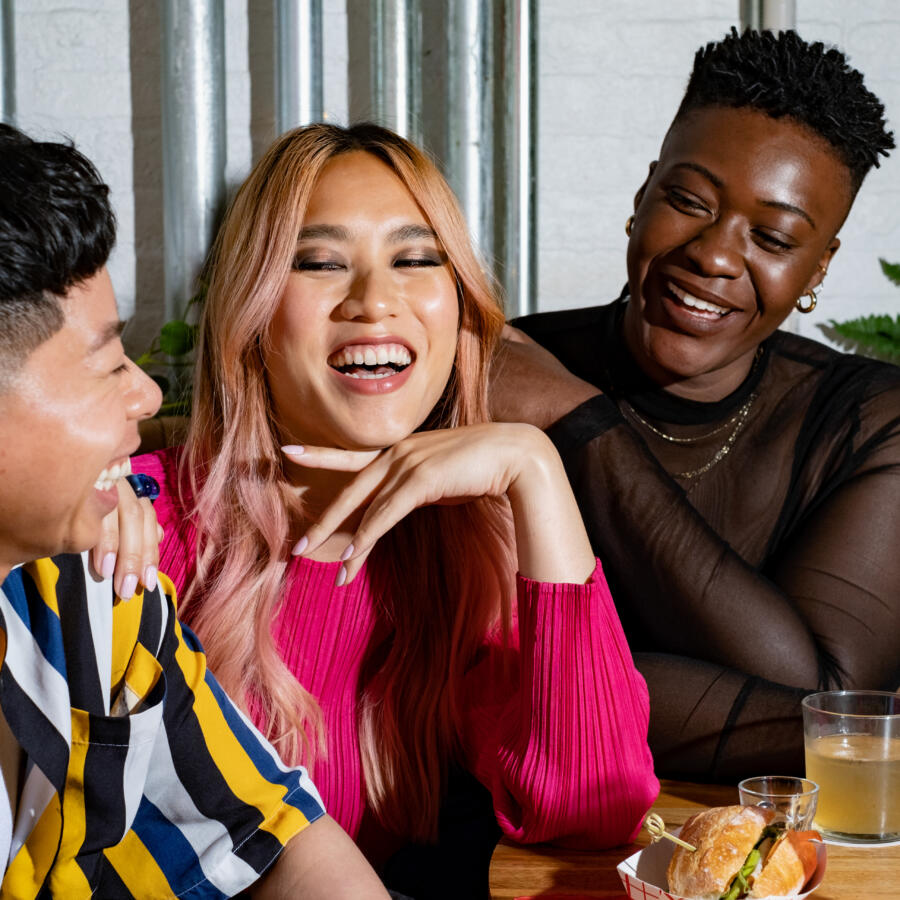 A group of friends of varying genders laughing over drinks 2