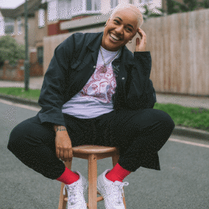 Person smiling on a stool outside