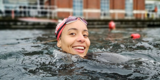 A smiling person's head emerging from a swimming pool