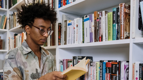 A young person reading a book in a library