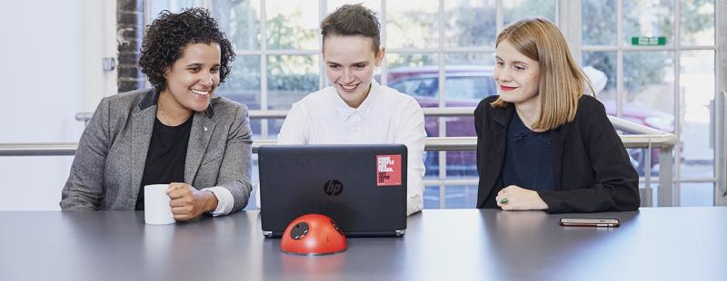 Three colleagues around a laptop