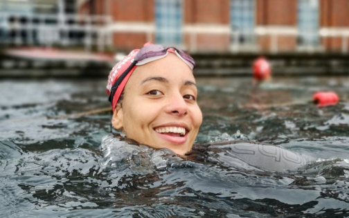 A smiling person's head emerging from a swimming pool